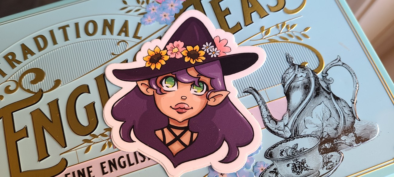 A purple haired, green eyed witch with a flowercrown witch hat.