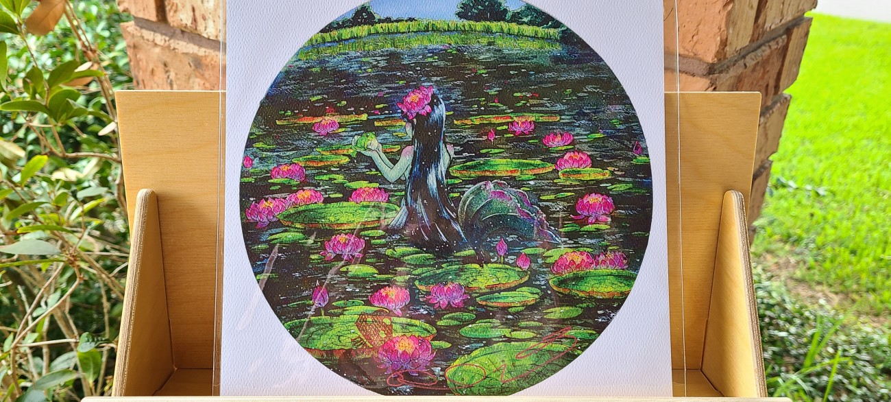 A mermaid in a swamp, surrounded by huge lilypads.  She's holding up a frog.