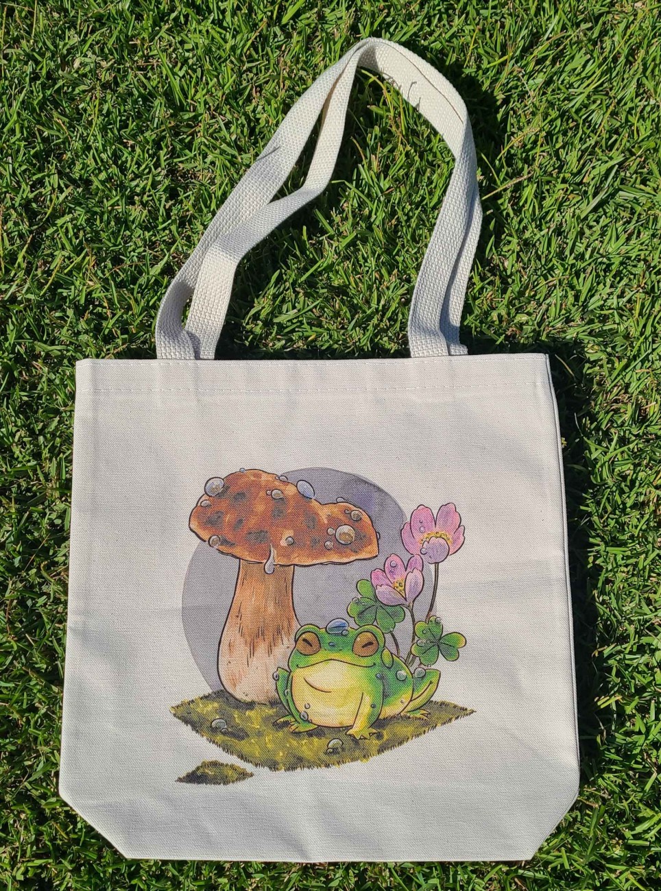 Natural canvas tote bag with my mushroom frog illustration printed across it.