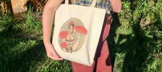 Natural cotton tote bag featuring a girl wearing a red straw hat, surrounded by red topped fly agaric mushrooms.